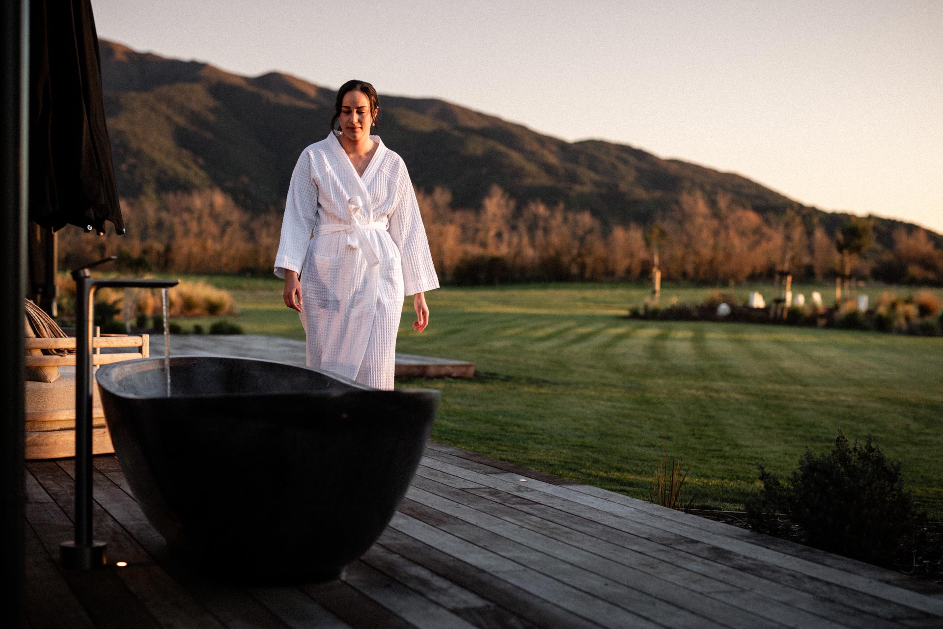 Outdoor stone bath on the deck at sunrise at Whakahā