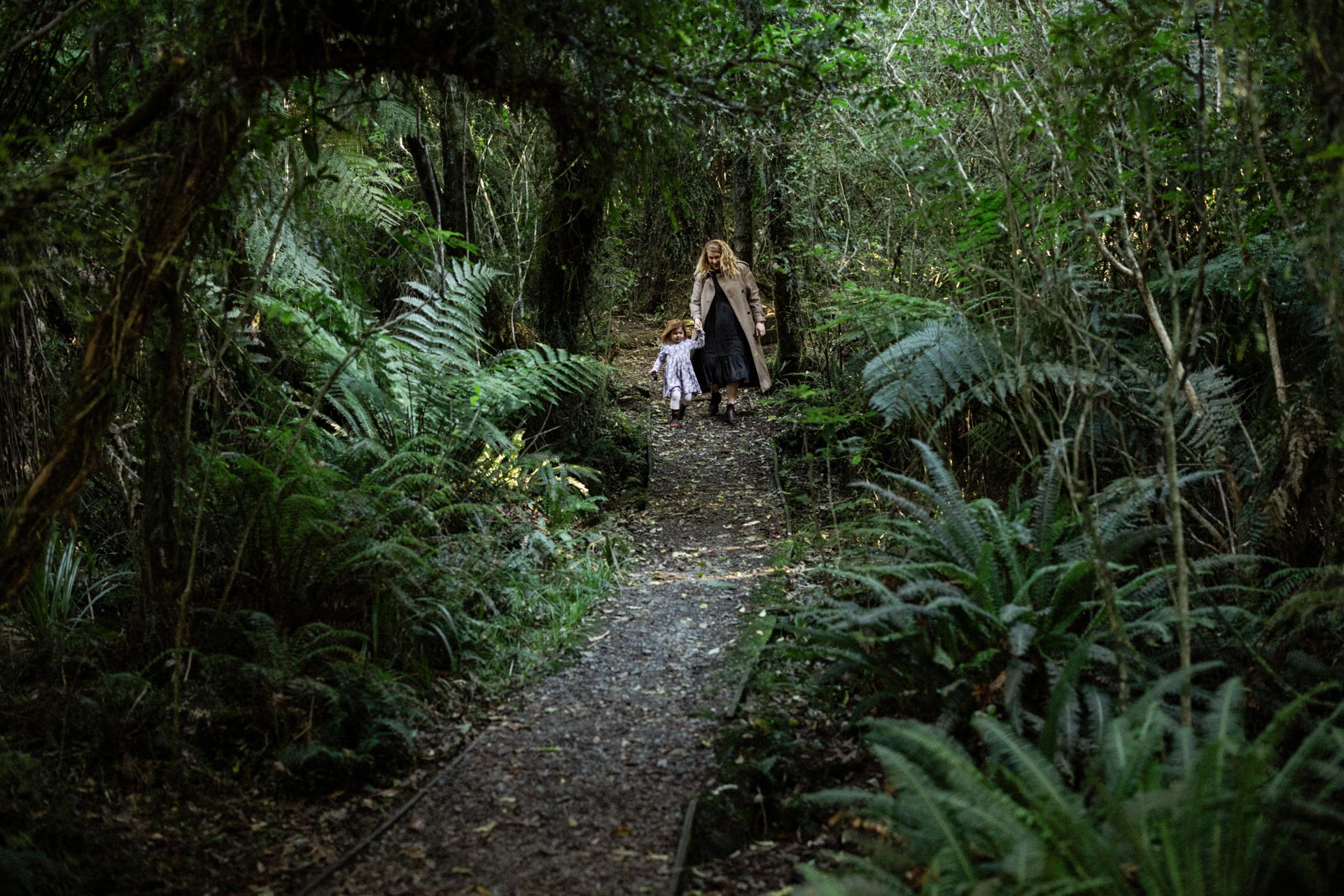 Mother and daughter walking a fern-lined path in Peel Forest