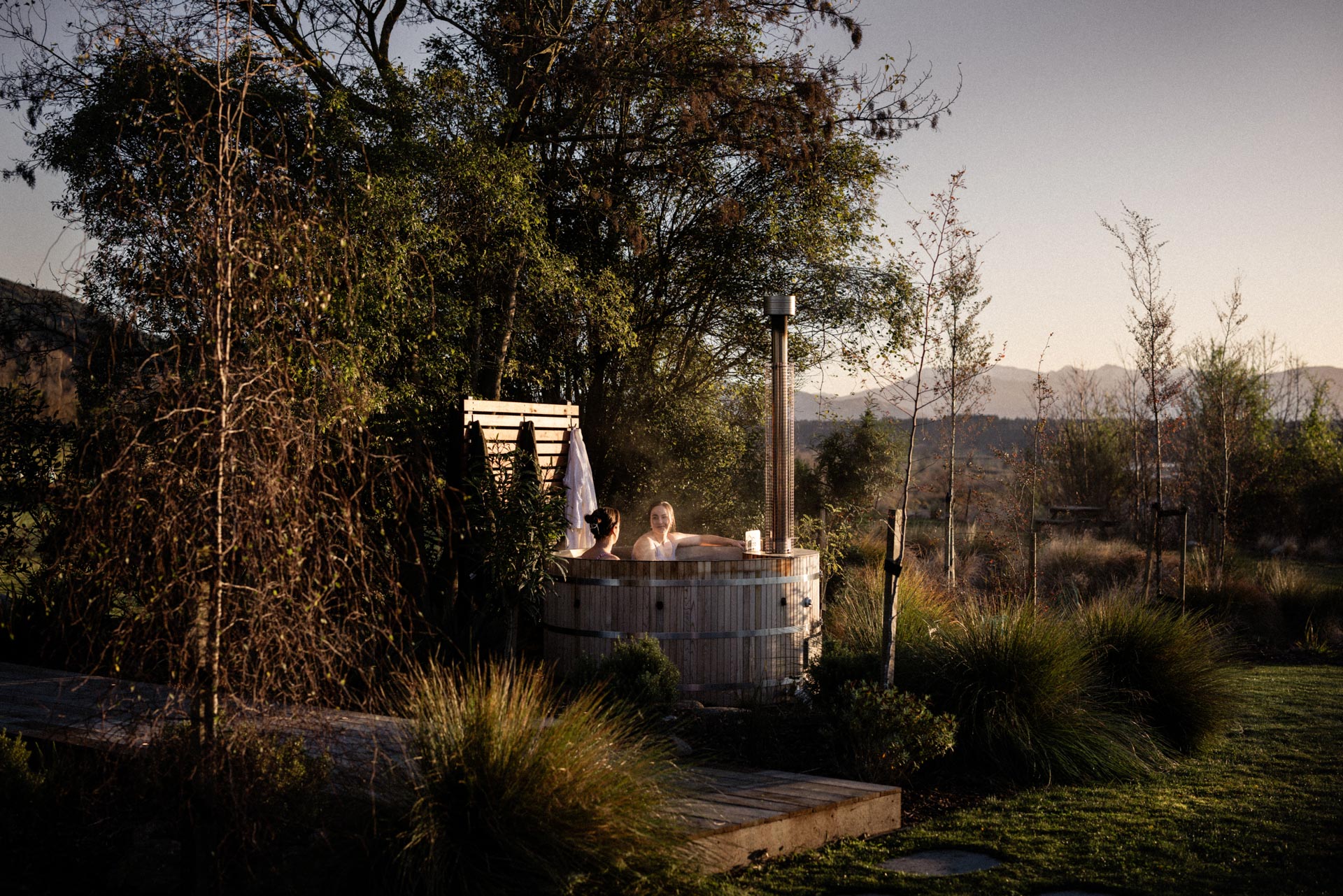 Wood-fired hot tub under the kōwhai trees at Whakahā