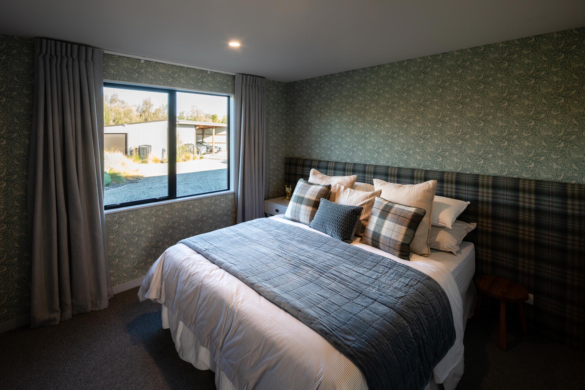 Third bedroom configured as a super king with plaid headboard and botanical wallpaper