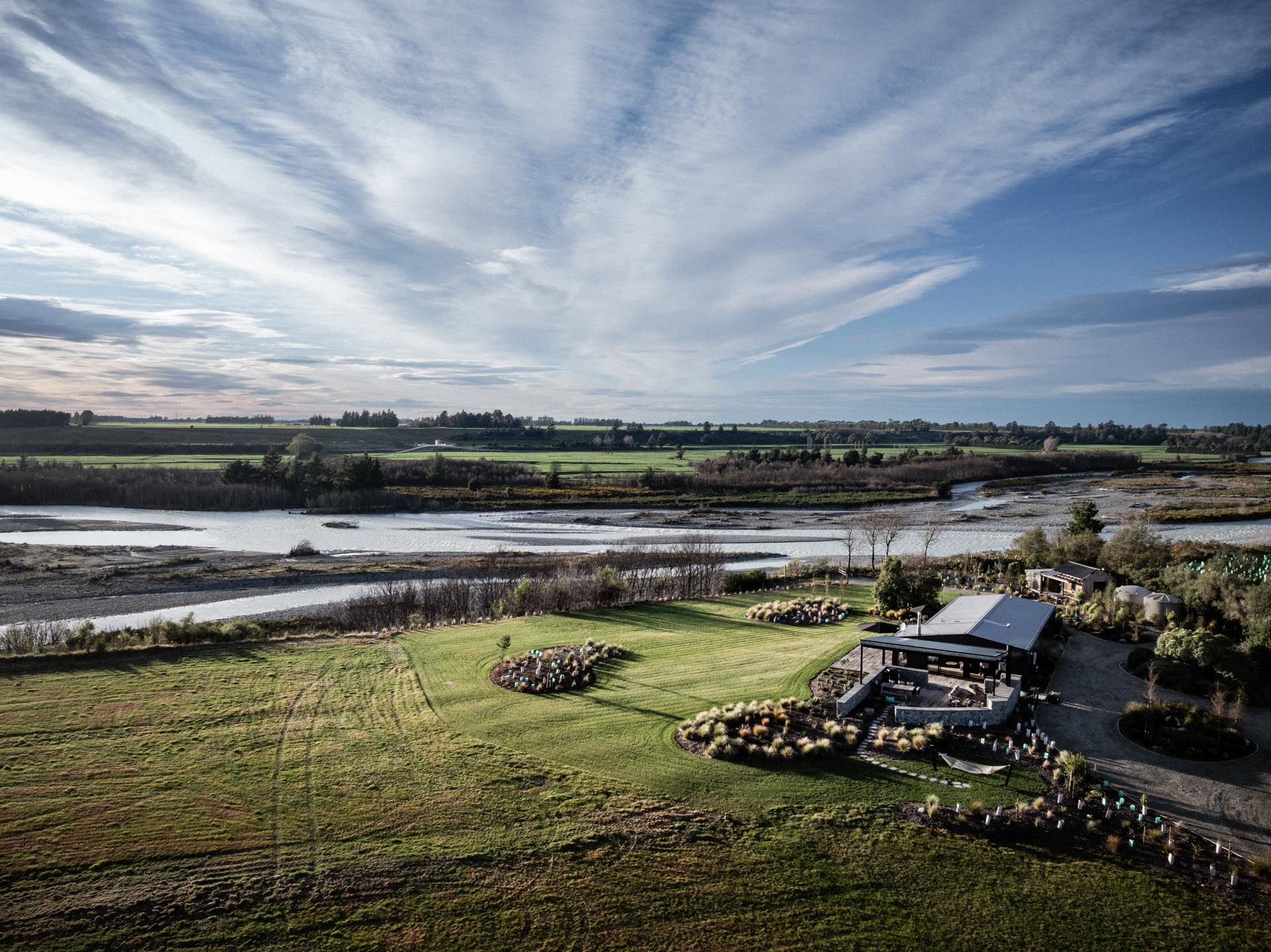 Aerial view of the house at Whakahā beside the braided Rangitata River under wide skies